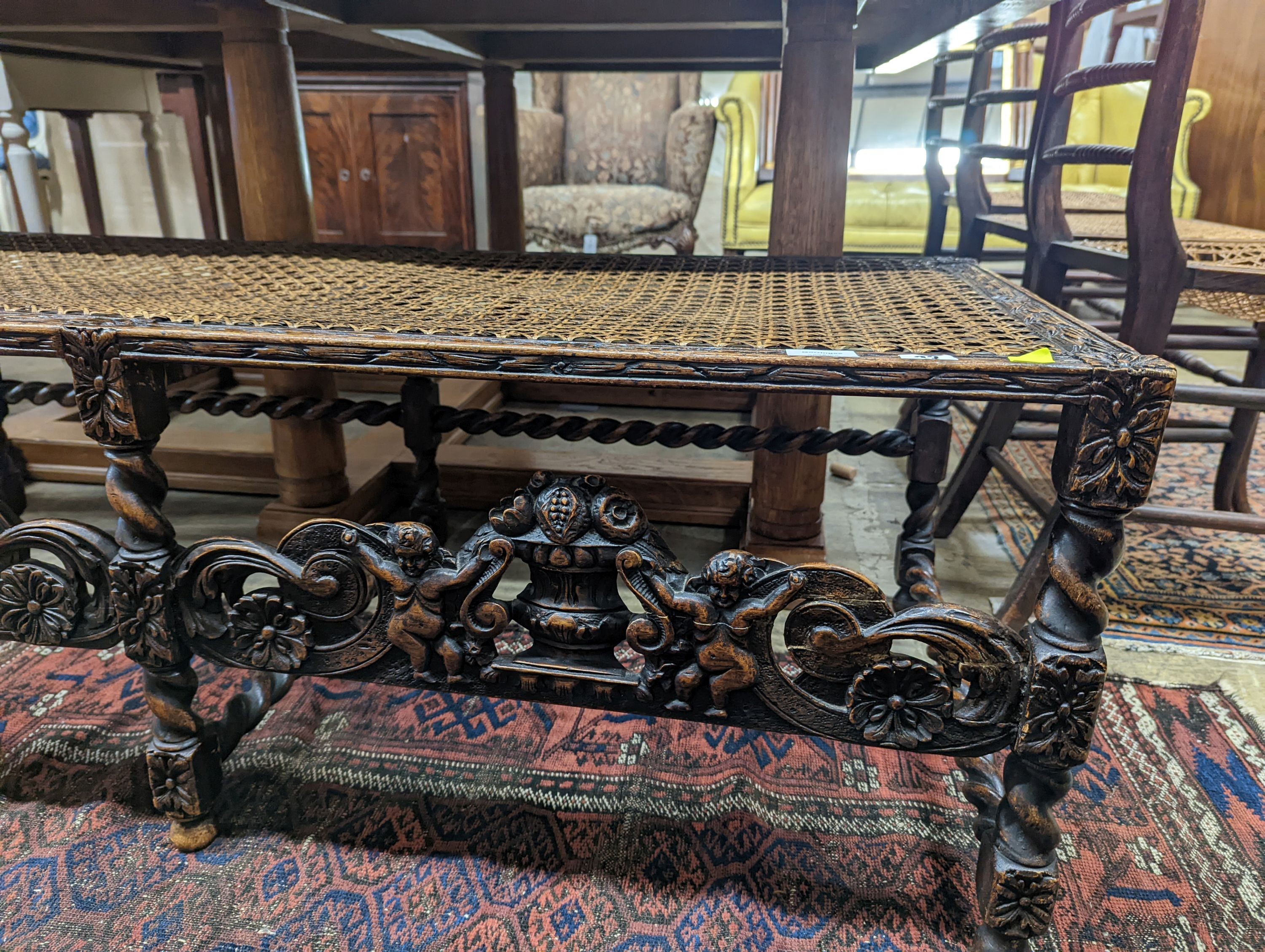 A 1920's Carolean style oak and cane work window seat, length 130cm, depth 58cm, height 44cm